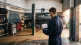 Mechanic in a UK garage workshop checking a booking confirmation on a tablet beside a car on the lift